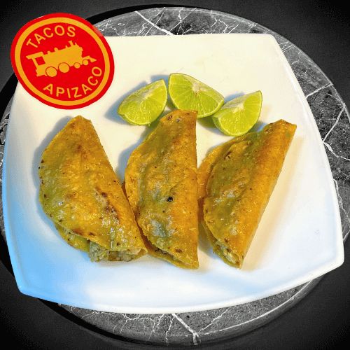 Tres quesadillas de seso doradas, con limones en un plato blanco.