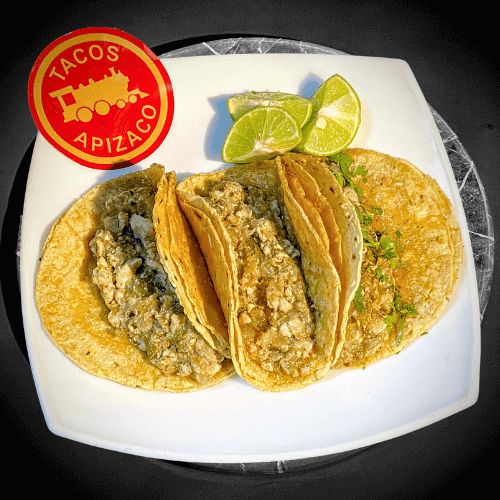 Tres tacos de seso en tortilla de maíz con cilantro, con limones en un plato blanco.